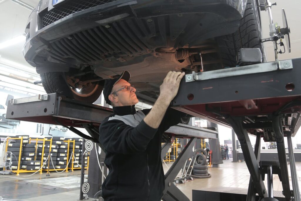 Man in Black Jacket Standing Under the Vehicle