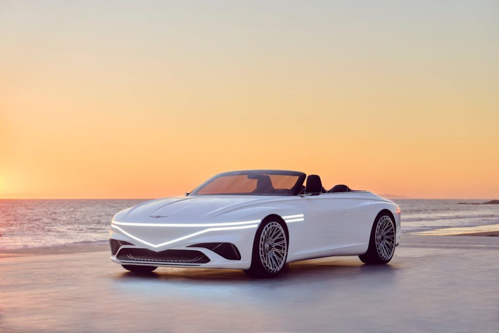 White Genesis Car on the Shore of a Beach Under Golden Sky